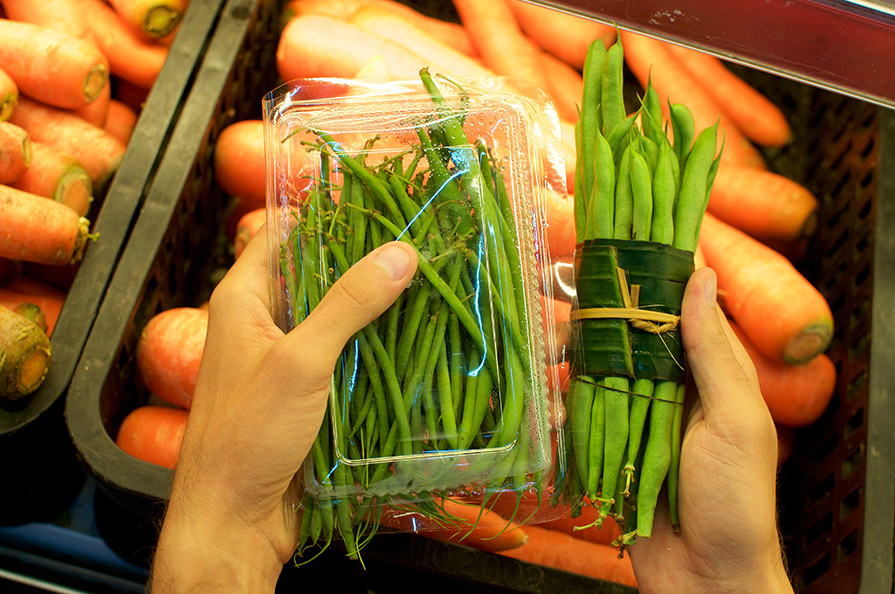 Green Beans one set in a plastic container another wrapped in a leaf
