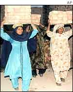 Women labourers carry bricks at a construction site in Pakistan