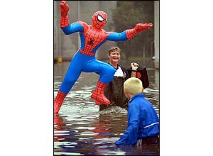 Ally Allan carries an inflatable Spiderman figure across flooded Cockenzie Street, Glasgow