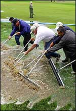 Groundskeepers and local firefighters push standing water from the second fairway