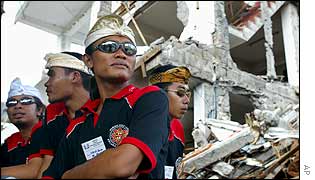 Balinese security guards watch over preparations for the grand purification ceremony at the blast site in front of the Sari Club in Kuta, Bali,