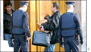A French investigator carries evidence into a police station