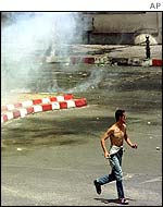 Demonstrator runs away from police tear gas 