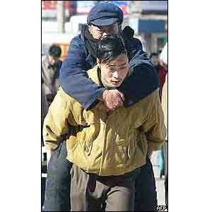 An elderly man is carried as people rush toward the train-ticket counter at Beijing station