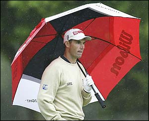 Padraig Harrington shelters under an umbrella