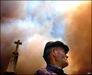 Man is shadowed by a church cross as smoke gathers above him