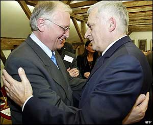 Guenter Verheugen (L), EU Commissioner for Enlargement and former Polish Prime Minister Jerzy Buzek hug during a conference in Warsaw in March 
