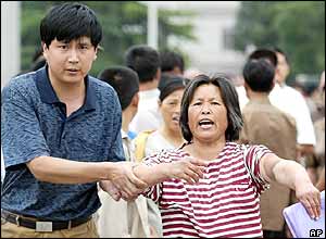 A Chinese woman yells and points to an injury on her arm as a plain clothed policeman detains her in Beijing's Tiananmen Square, June 4, 2004 
