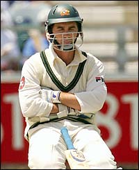 Australia's Justin Langer kneels on the ground 