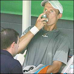 Nicolay Davydenko is treated by the trainer after complaining of problems breathing