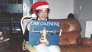 Liz holding up a law calendar and wearing the dreaded Santa hat.