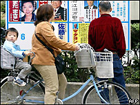 Japoneses lendo cartazes de campanha eleitoral