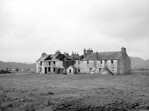 Black and white view of a two-storey block of workers' houses at Bonawe Furnace. the centre of the block is abandoned with no roof and missing windows.