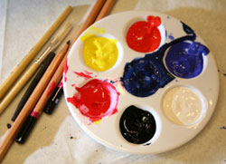 Image of a palette filled with paint and paintbrushes, courtesy Glynn Vivian Art Gallery