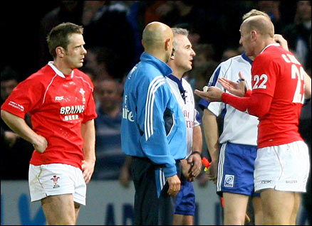 Referee Chris White is confronted by angry Welsh players