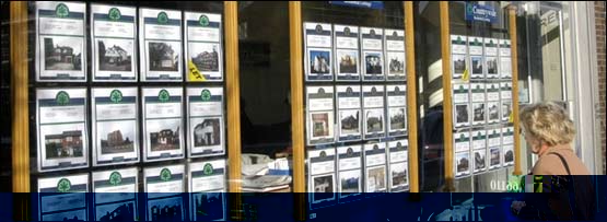 Somebody looking in the window of an estate agent's shop