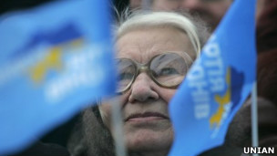 Жінка поруч із прапорцями Партії регіонів