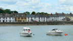 Boats in Garlieston Harbour. A row of single and two-storey buildings line the promenade behind.