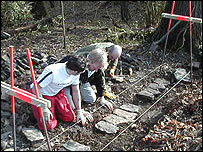 People repair a dry stone wall