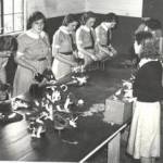 Schoolgirls from Chipping Sodbury Grammar School, at the Food Office, in Sodbury Rural District Council in Lilliput Court, during 1939. Here they are assembling gas masks. They were told to spend some part of their summer term in the school year with this task. From left to right, unknown, Pearl Blakeney (now deceased), Nora Elsa (now deceased), Barbera Woodman, Elsie Broom, not known, Iris Wathern, not known. Moira was in a different group to these girls, so does not appear in this picture.