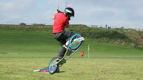 A dirt surfer being lifted off the ground by his kite