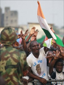 Photo showing a soldier monitoring a crowd of people waving flags