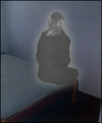 A lady perches on a bed at night