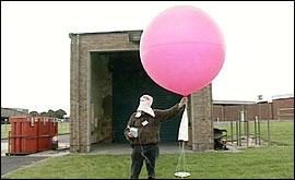A man holding the radiosonde. This is a Hydrogen-filled balloon about 1 metre across - attached to a cradle in which the sensors and radio transmitter sit