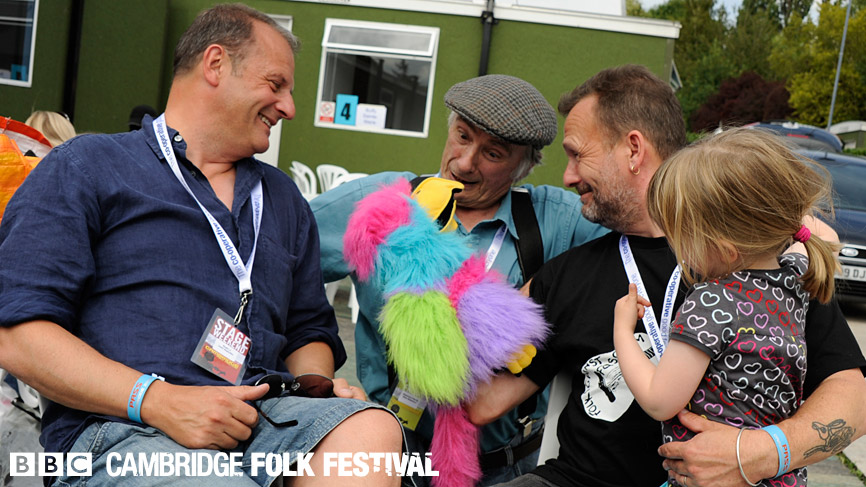 Mark Radcliffe, Mike Waterson and Martin Simpson and Molly Simpson relax backstage in the Friday sunshine.