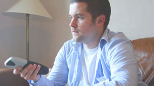 Charlie Swinbourne, remote control in hand, closely watching the TV subtitles