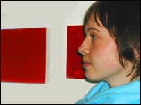 Artist Leanne Narewsky standing by art by fellow OHOS artist Emily Smeaton