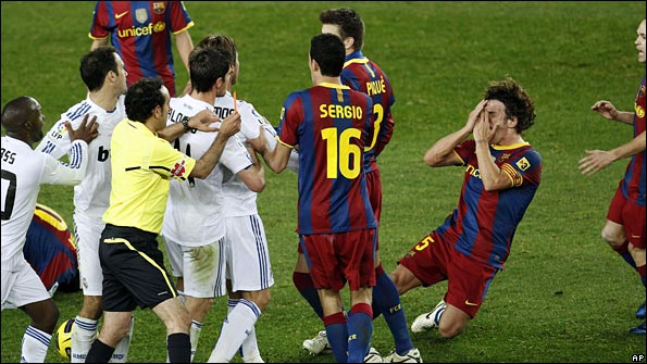 Carles Puyol goes to ground after being pushed in the face by Sergio Ramos
