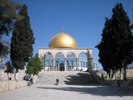 Gold dome of the Dome of the Rock mosque, a blue tiled building, framed by trees