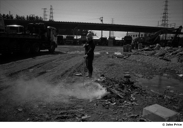 A worker sweeps pieces of wood into a fire
