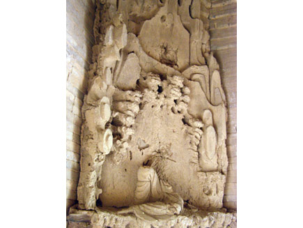 The Da Qin nativity scene, a stone carving that is left barely recognisable by erosion and damage. It shows gently curving mountains surrounding a central human figure, of whom only the legs remain