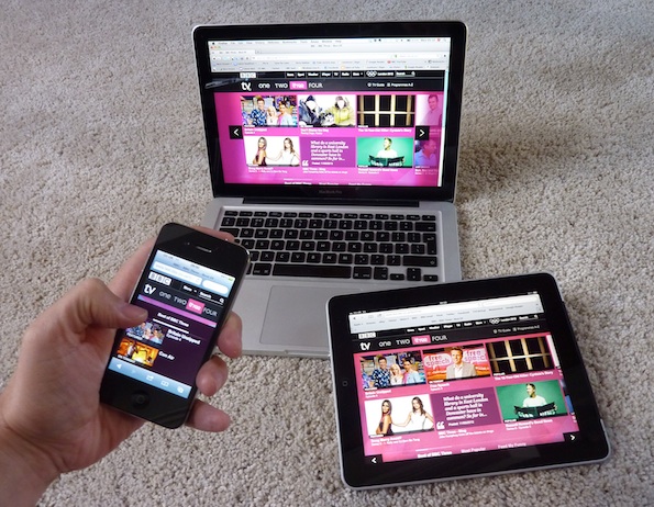 Hand holds the BBC Three homepage on a mobile phone, in front of a tablet and a laptop showing the same.