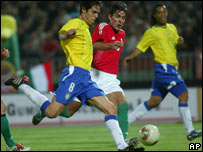 Kaká carrega a bola observado por Ronaldinho Gaúcho