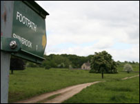 Sign to Swinbrook with St Oswald in the distance