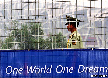 A security guard walks past the fence outside the Olympic stadium