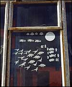 Dinosaur cut-outs stuck to a window.