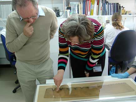 Roger Bolton and Pnina Shor looking at a scroll in a glass frame