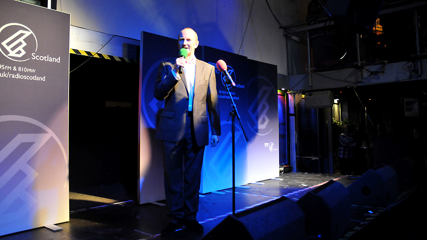 Fred introduces the last comedian of the night, Miles Jupp.