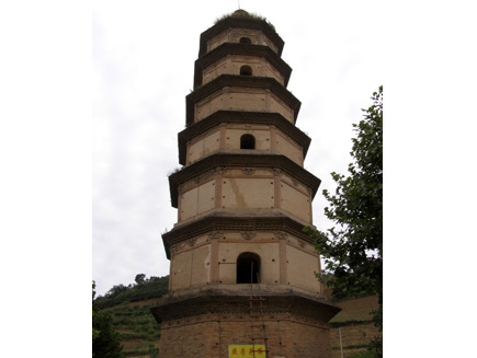 Da Qin Pagoda, a tall buff-coloured building dating from 800CE. A sign with Chinese characters hangs at the base and a ladder made of sticks is leaning up against the bottom window