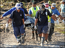 Rescue workers recover the body of a woman from the debris of tsunami devastated Lalomanu in Samoa on October 1, 2009