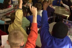 Picture shows pupils with arms raised in a school classroom