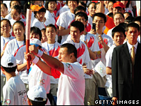 Former Chinese national champion boxer Abdul Xukur carries the Olympic Torch past a crowd in People's Square on June 17, 2008 in Urumqi, Xinjiang.