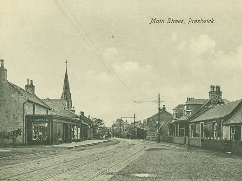 Black and white view of Main Street, Prestwick, showing tram-lines and a double-decker tram in the distance.