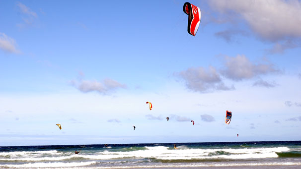 Kitesurfers harness the wind with their inflatable kites and use this to power across the waves on their surfboard, or kiteboard.