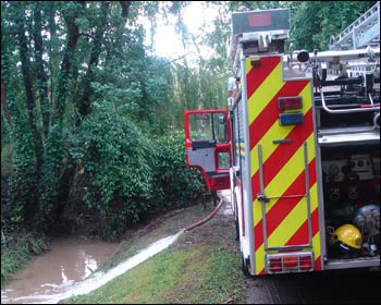 A fire engine pumping water into the river