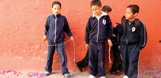Mexican schoolboys in uniform stand in front of terracota wall
